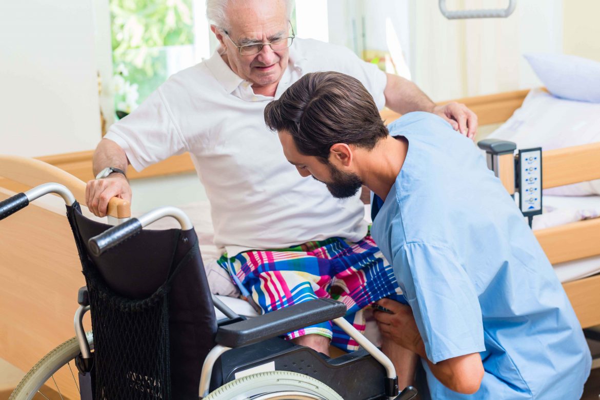 Elderly care nurse in retirement home helping senior from wheel chair to bed