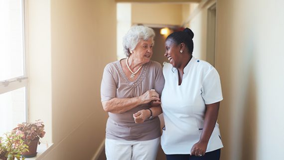 Happy female caregiver and senior woman walking together
