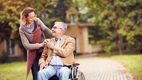 senior man in wheelchair with caregiver daughter.